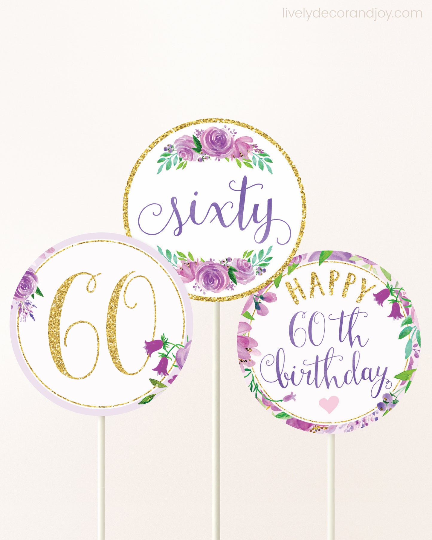 Three DIY toppers attached to lollipop sticks. They show printable cupcake topper designs with purple watercolor flowers.