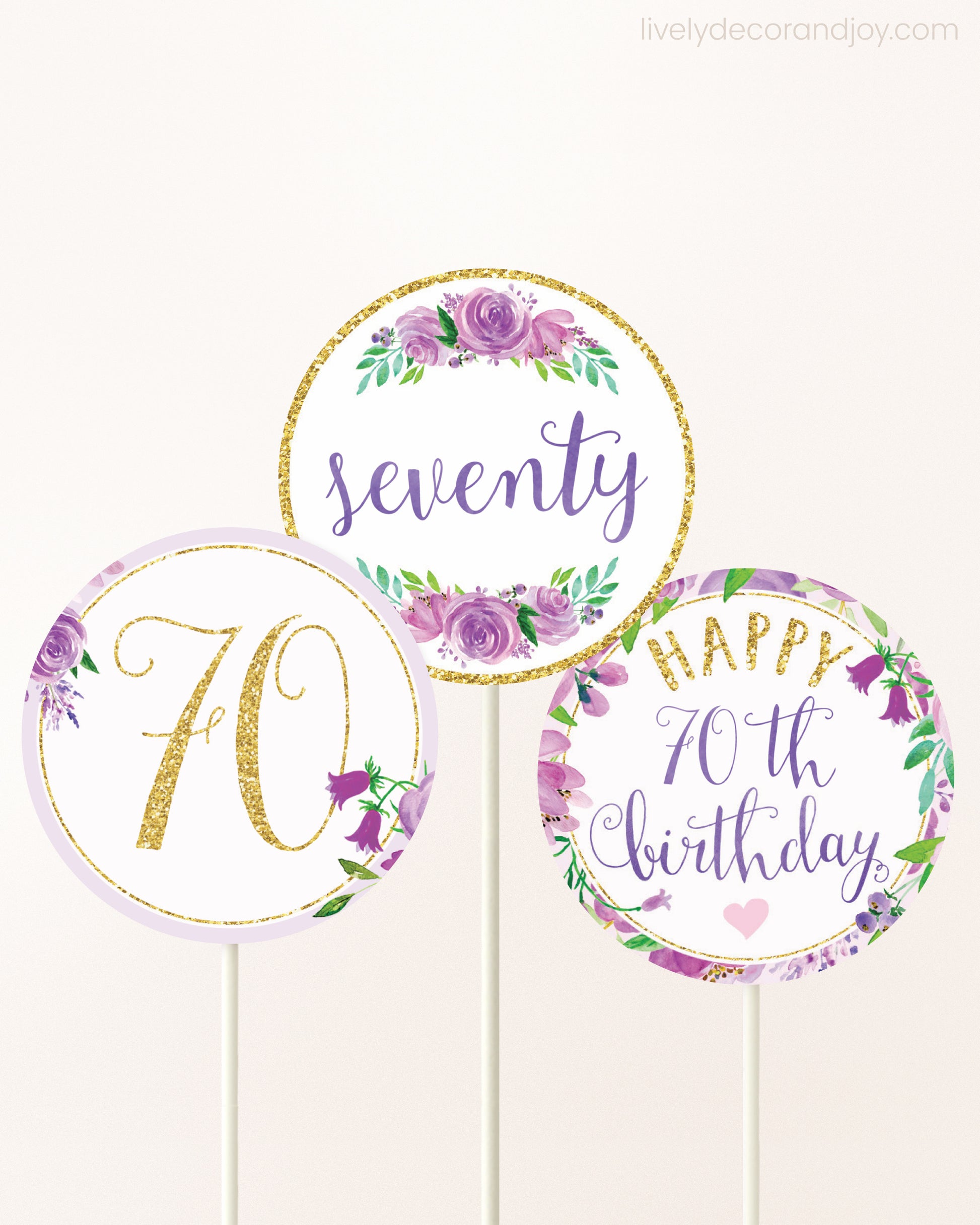 Three cupcakes toppers attached to lollipop sticks. They feature purple watercolor floral designs and purple and gold handwritten text.