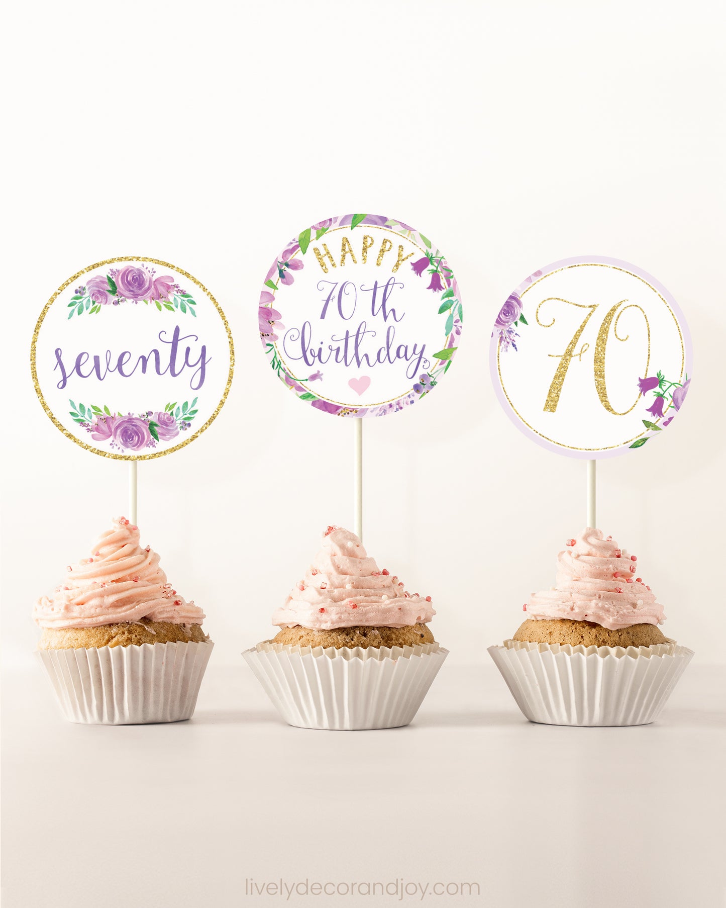 Three cupcakes on a dessert table. Each has a round cupcake topper with purple watercolor floral designs and purple and gold letters.