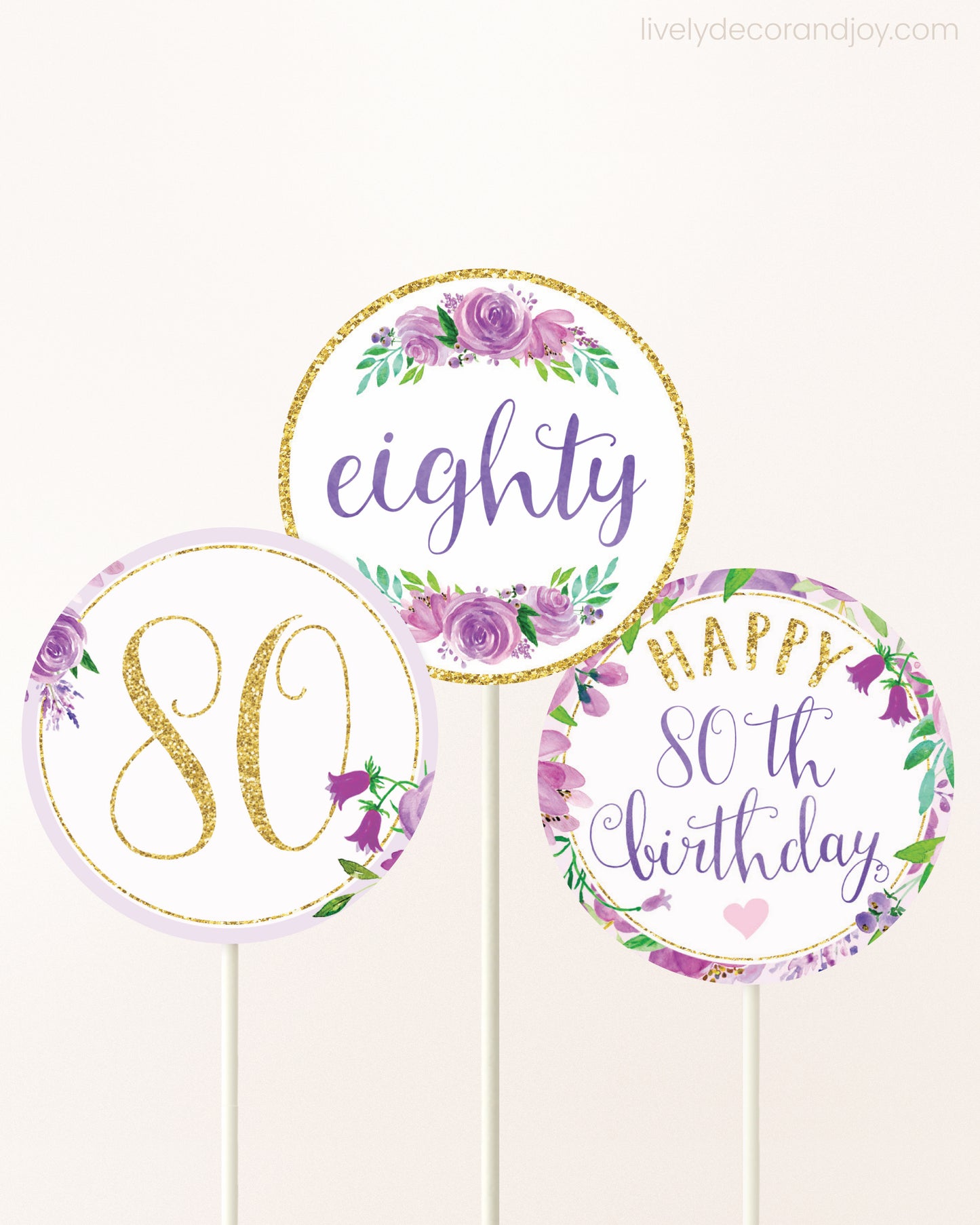 Three DIY toppers attached to lollipop sticks. They show printable cupcake topper designs with purple watercolor flowers.
