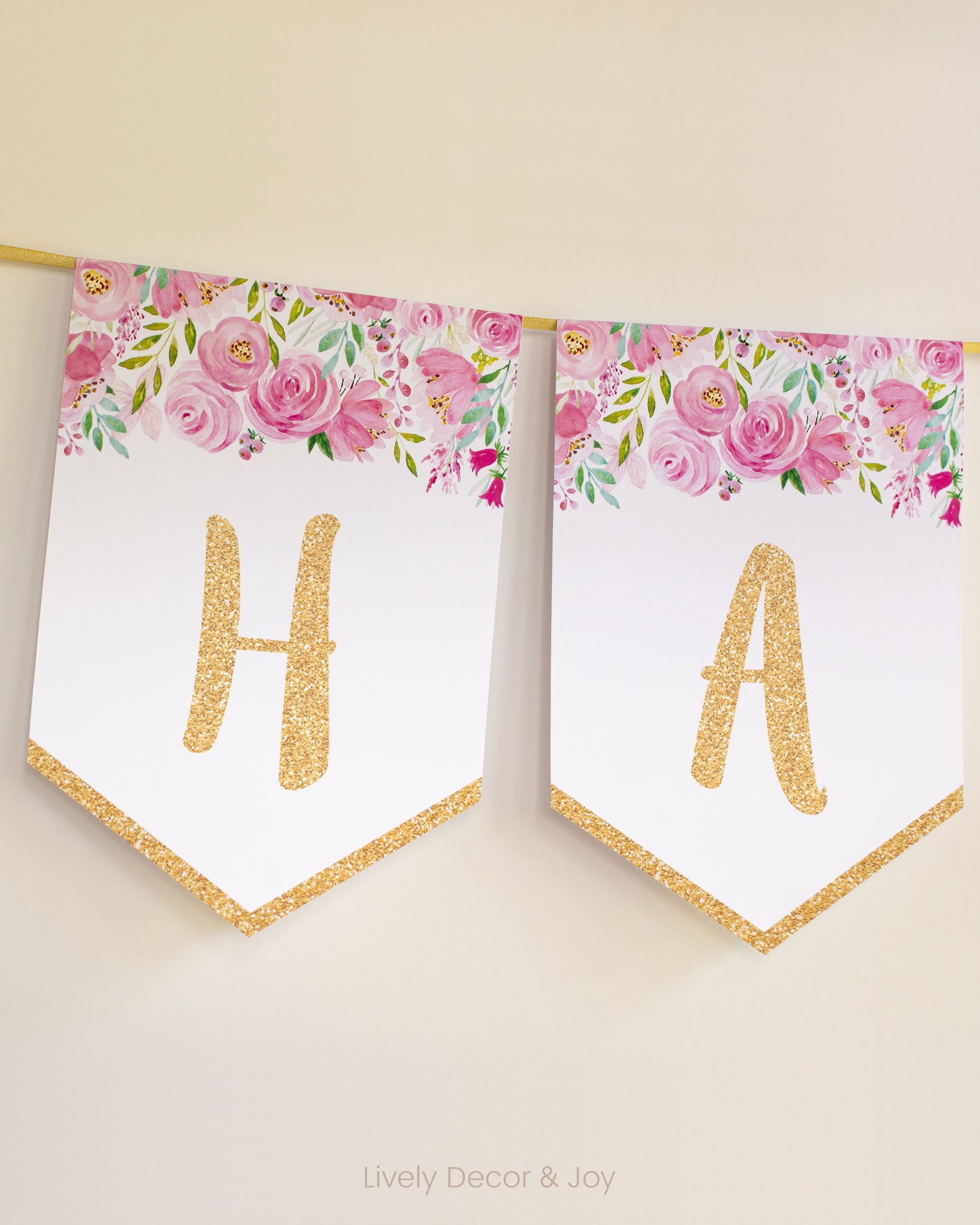 Casual banner flags on a wall with handwritten letters in gold: a floral Happy Birthday banner or engagement banner.