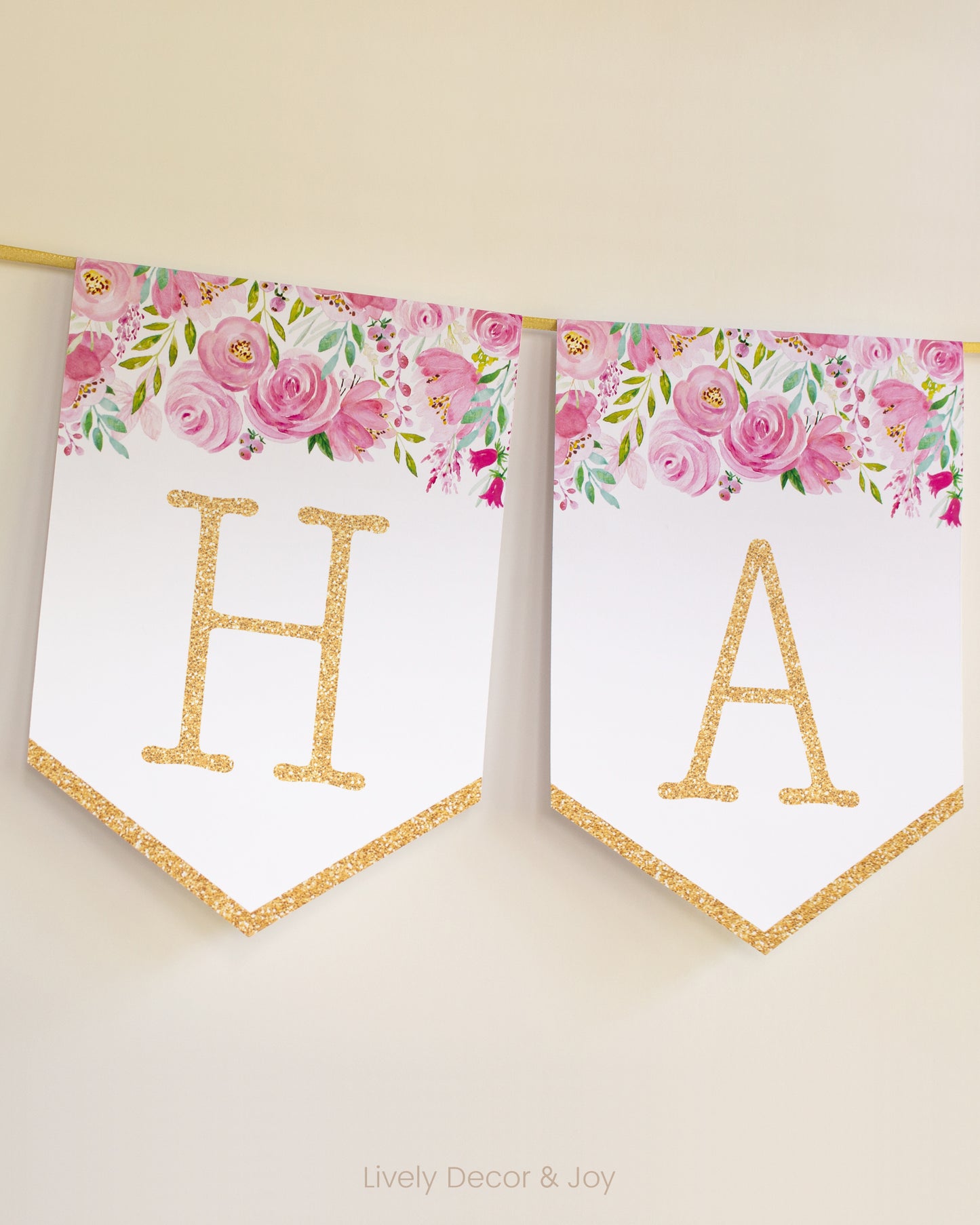 Vintage banner flags on a wall with typewriter letters in gold: a Happy Birthday banner or wedding sign with pink flowers.