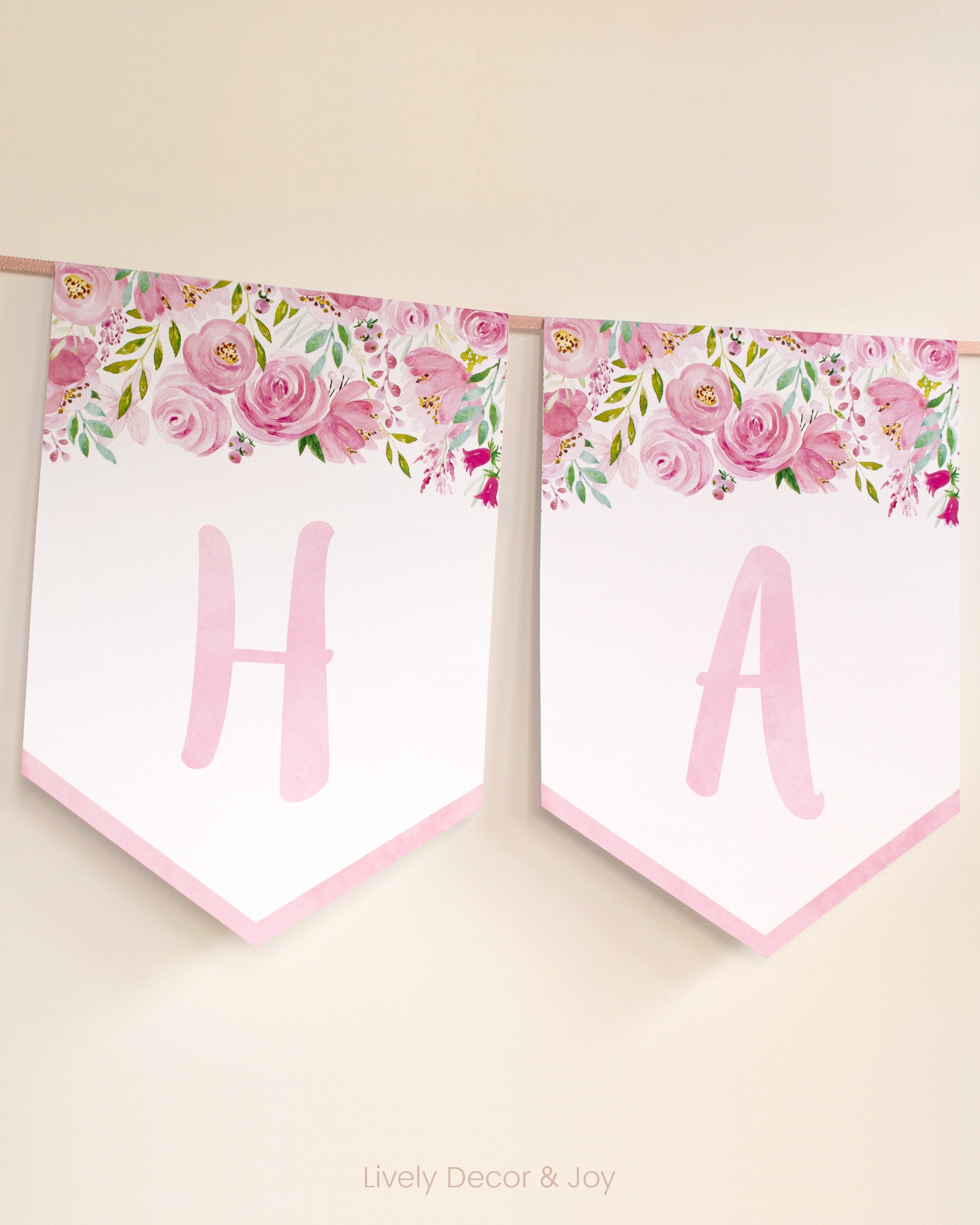 Casual banner flags on a wall with handwritten letters in pink: a floral Happy Birthday banner or engagement banner.