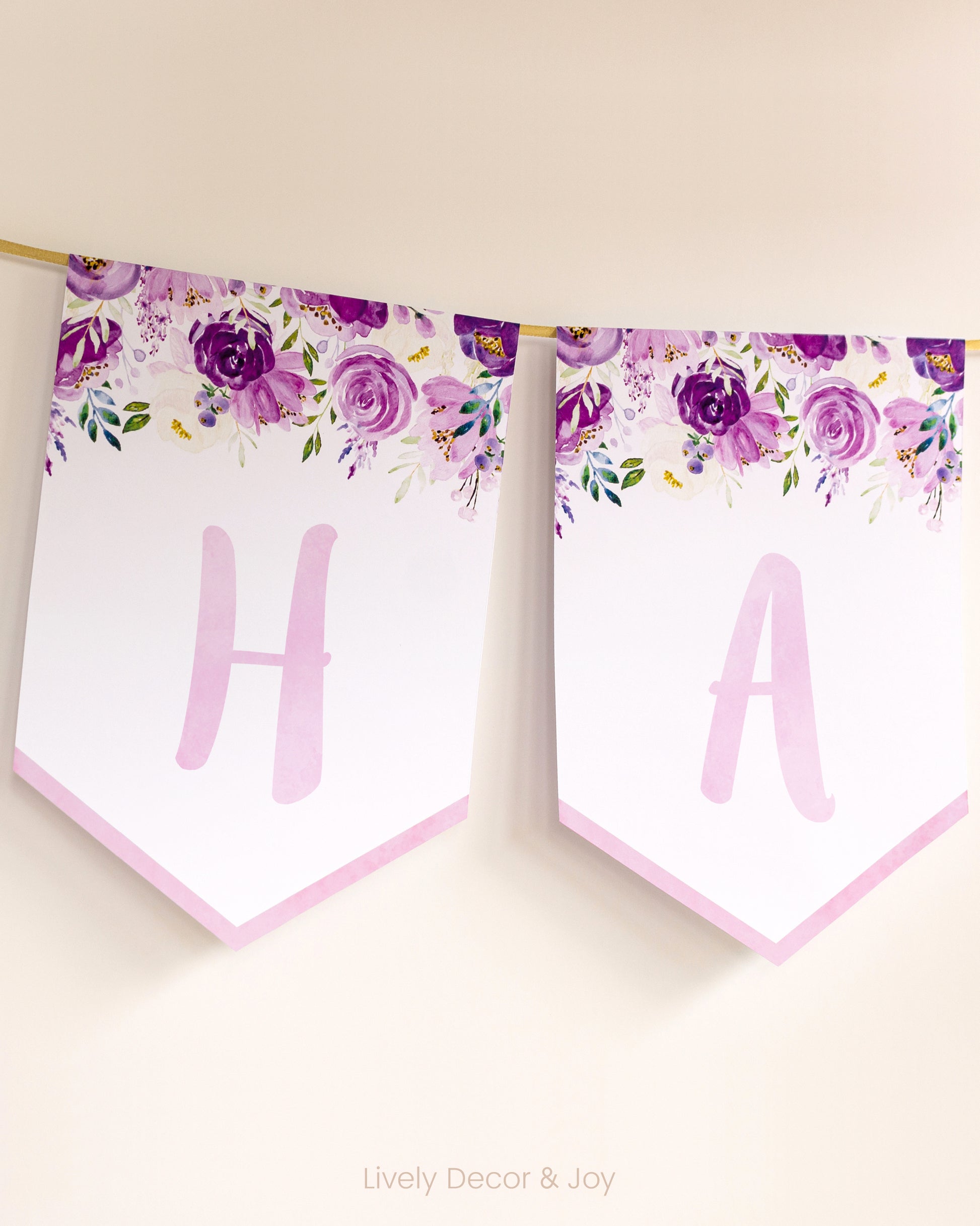 Casual banner flags on a wall with handwritten letters in pink: a floral Happy Birthday banner or engagement banner.