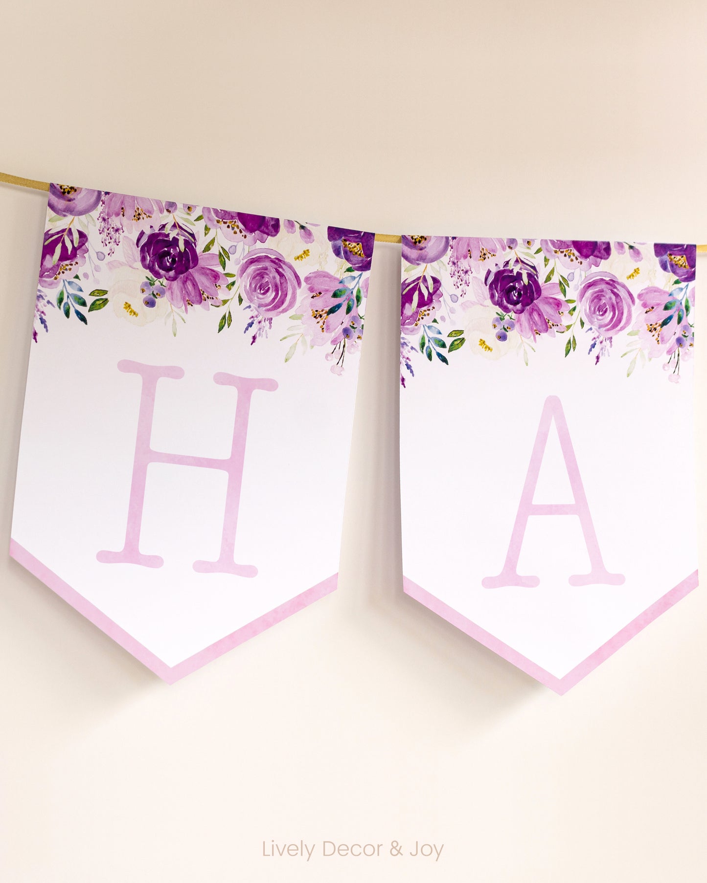 Vintage banner flags on a wall with typewriter letters in pink: a Happy Birthday banner or wedding sign with purple flowers.