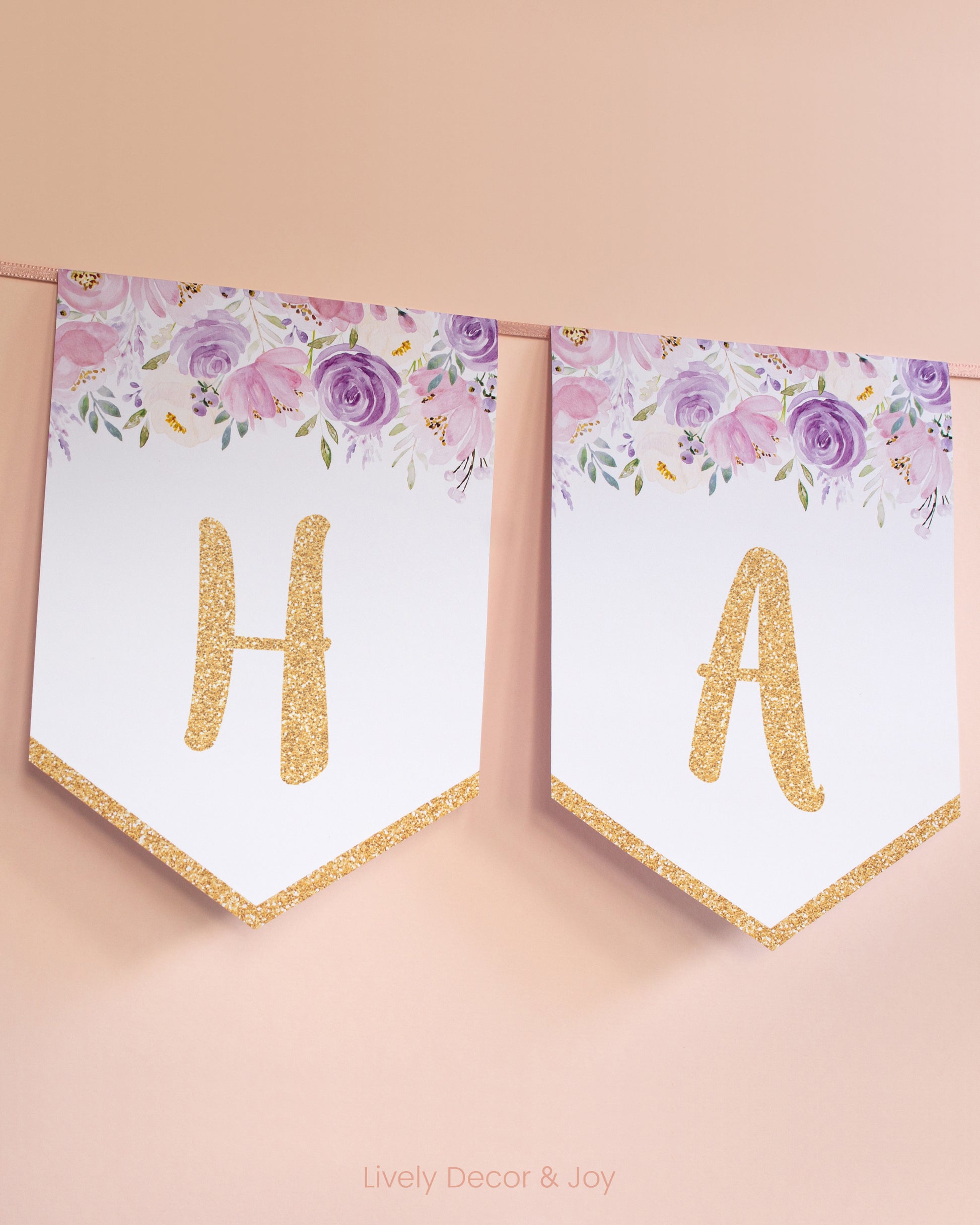 Casual banner flags on a wall with handwritten letters in gold: a floral Happy Birthday banner or engagement banner.