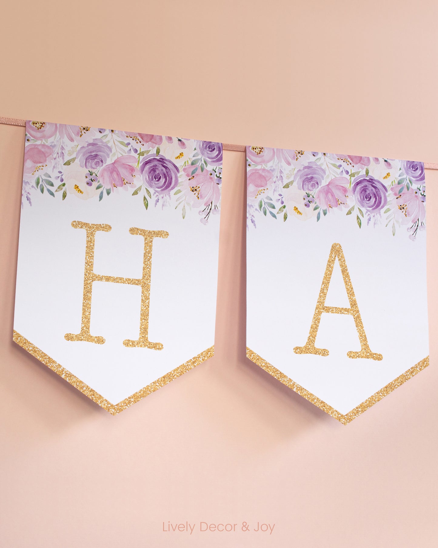 Vintage banner flags on a wall with typewriter letters in gold: a Happy Birthday banner or wedding sign with blush flowers.
