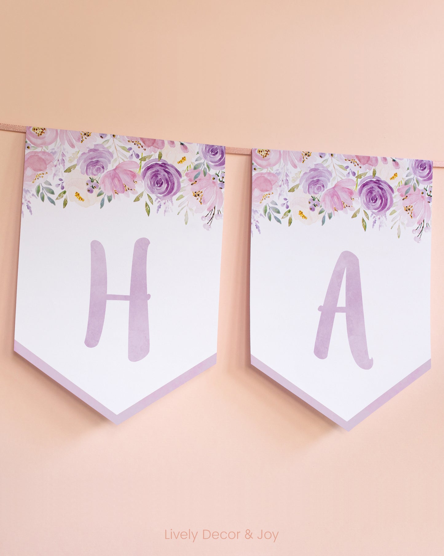 Casual banner flags on a wall with handwritten letters in purple: a floral Happy Birthday banner or engagement banner.